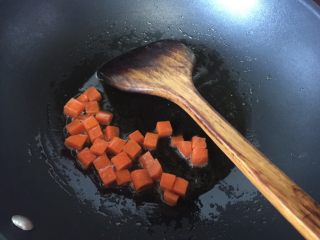 浓香板栗咖喱鸡肉蒸饭,锅里热油后放入胡萝卜粒炒香