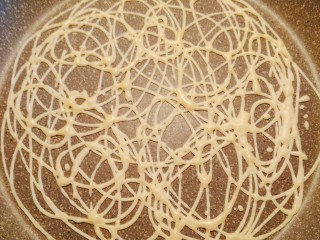 ins网红蕾丝鸡蛋卷,拿住裱花袋在预热好的平底锅上一边画小圈⭕⭕一边挤面糊，让每个圈圈都相连，形成一个网格状，自己按自己喜欢的形状画圈就可以；