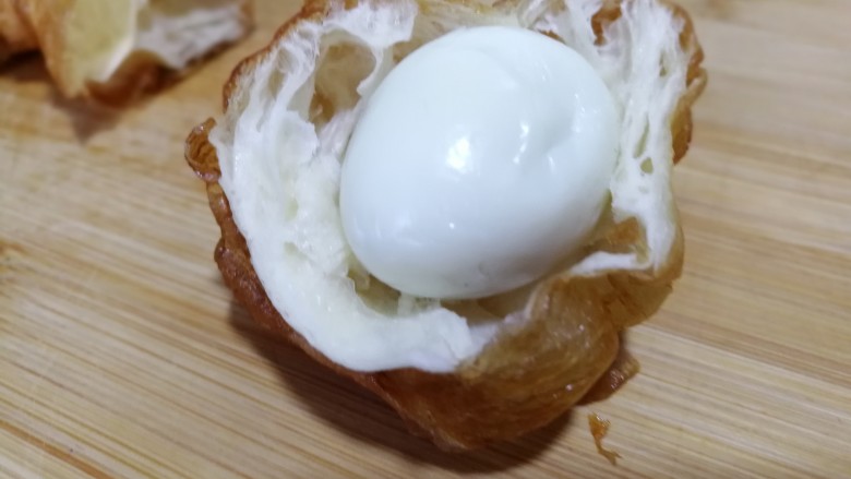 油条豆乳抱蛋,取一个鹌鹑蛋用油条包住。
