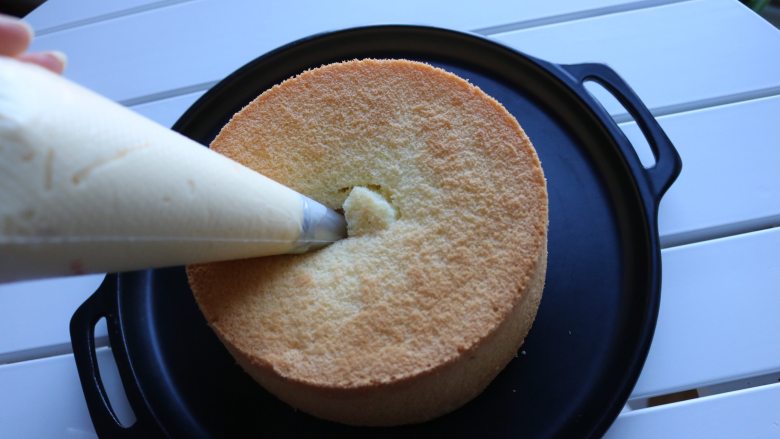 爆浆海盐奶盖蛋糕,准备一个圆形裱花嘴，装入裱花袋中，然后将海盐芝士装入裱花袋中，轻轻地将奶盖酱挤入蛋糕中间；