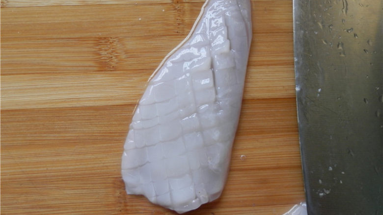 砂锅爆炒鱿鱼,全部切好后，将鱿鱼转个方向，用倾斜45度的刀，切间隔为3毫米宽的条，勿切断鱼身。