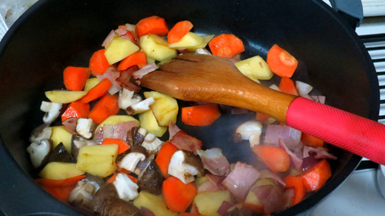 浓郁味香的【培根奶油炖菜】,土豆红萝卜块入锅翻炒，再加入香菇炒至半熟