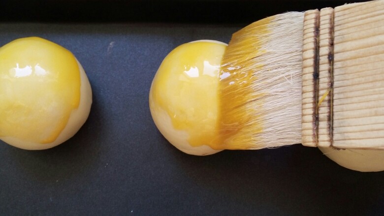 蛋黄酥(黄油版),均匀的刷在蛋黄酥表面 如果碗里还剩蛋黄液可以反复刷几次