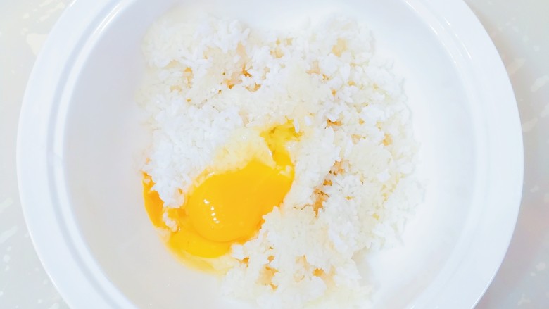 米饭鸡蛋饼,将米饭倒入一个稍微深一点大一点的盆里，打入鸡蛋。