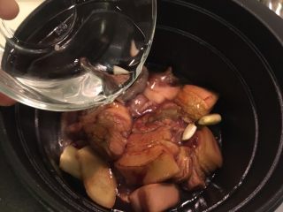 铁锅烧猪,加蒜、姜、香料包后再加入1碗清水