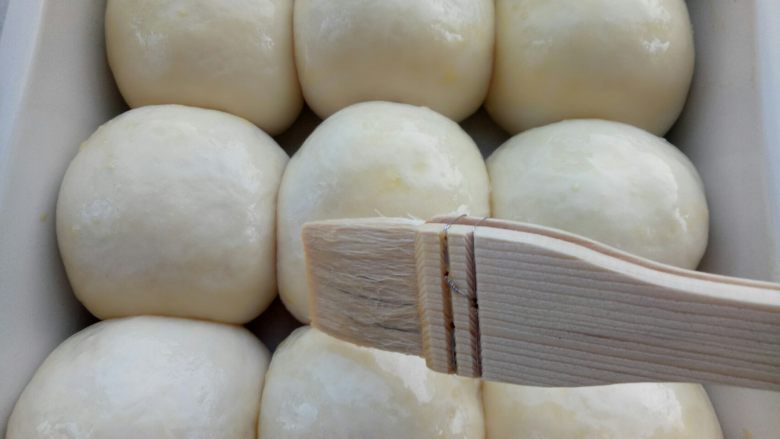 椰蓉小面包,用手指粘点面粉轻轻按一下发好的面团，如果慢慢回弹证明已经发好了，刷一层蛋液，烤箱180度预热。
