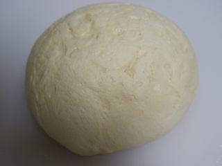 香葱培根芝士面包,发酵好的面团取出按压排气，边缘的大气泡拍掉。