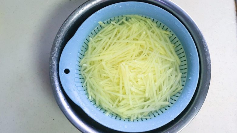 香葱胡椒土豆丝,把土豆丝放入沥水篮，再泡入清水中浸泡，为了去除多余的淀粉