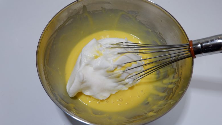 轻芝士蛋糕（6寸）,先取1/3蛋白加入奶酪糊中，翻拌均匀。