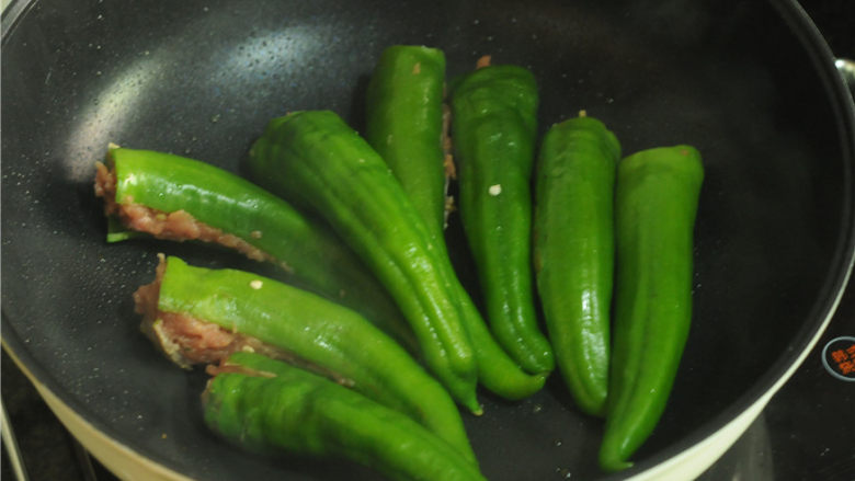 青椒酿肉,锅烧热，倒入少许油，烧热后将青椒摆在平底锅里煎，将有肉的一面朝下，小火慢煎