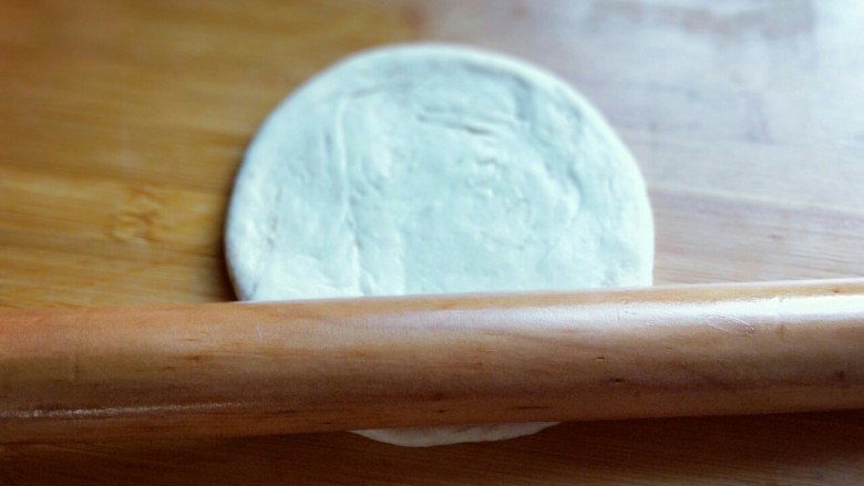 做饼＋老北京烧饼#电饼铛版#,将小面团立再面板上，用手心压扁，然后再用擀面杖擀开，约12cm左右圆形。