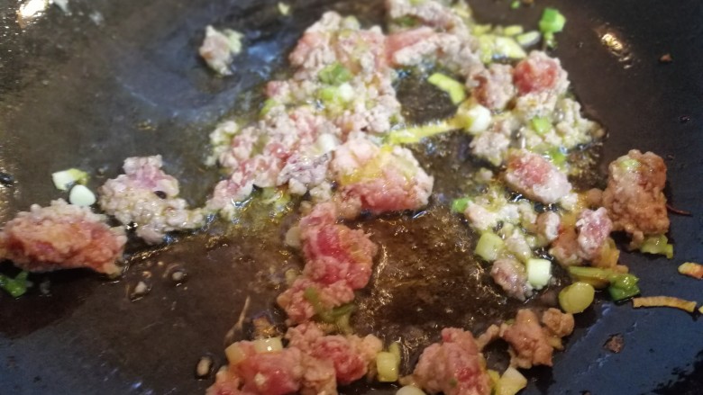 蛋裹肉碎炒蒜薹,锅内放油烧热倒入肉碎，葱花。