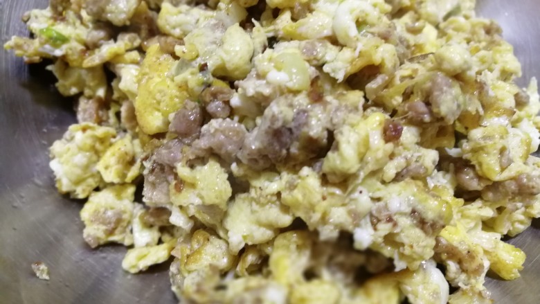 蛋裹肉碎炒蒜薹,蛋液裹在肉上面炒熟后盛着装在盘里备用。