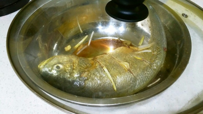 香辣黄花鱼,把多余的葱姜蒜塞进鱼肚，盖上盖子，腌制20~30分钟。