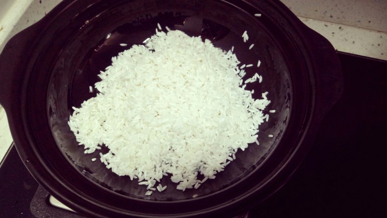 广式腊味煲仔饭,先把大米洗三四次，然后浸泡40分钟左右，用筛子滤干水分，记得不要再用手抓米了，会变碎的。砂锅无水，用刷子抹上一层油在锅底和锅壁。