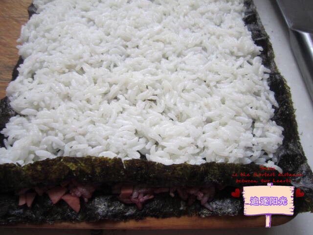花朵🌺寿司🍣,把铺好白色米饭的紫菜放到铺好的红色米饭的紫菜上。