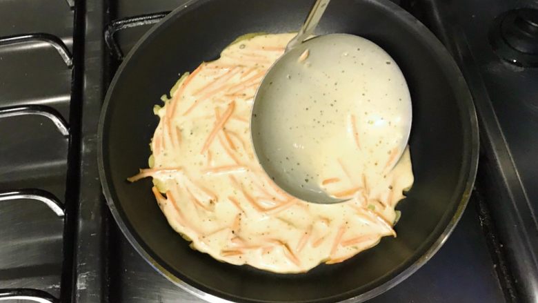 做饼+黑胡椒胡萝卜煎饼,用勺子迅速挤压面糊，让面糊均匀铺在锅底。