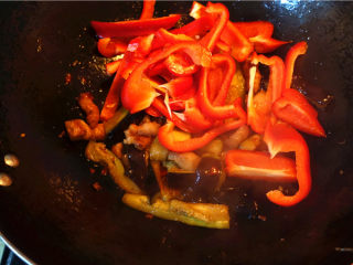 茄子甜椒烧五花肉,将甜椒放入锅里，翻炒。