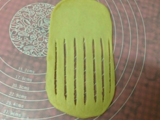 毛毛虫面包,取一个面团擀薄，用刮板在面片的一端切成一些等宽的长条（底部尽量薄一些0