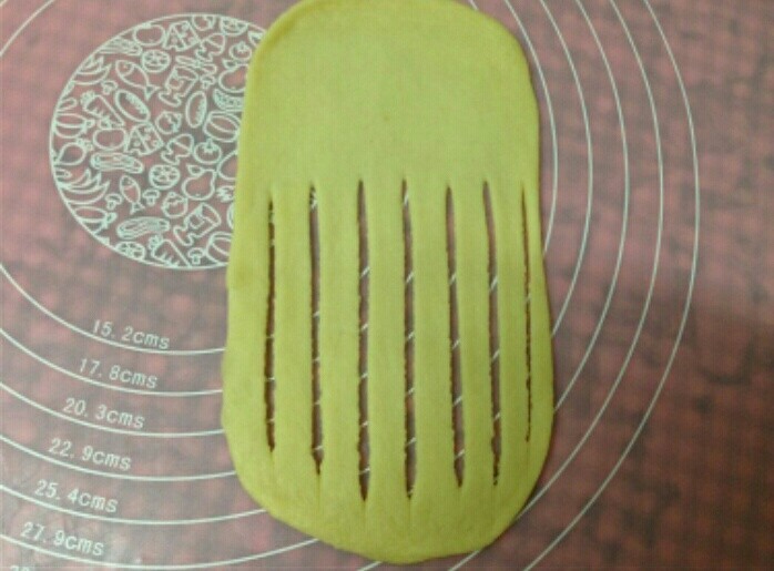 毛毛虫面包,取一个面团擀薄，用刮板在面片的一端切成一些等宽的长条（底部尽量薄一些0