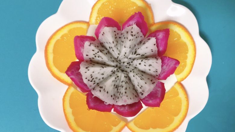 创意水果拼盘,先挑选中间的大片摆放在火龙果周围，像花瓣一样