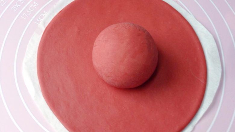 大红帽,再取一小块红色面团搓成圆球状，放在圆面饼的中央位置。