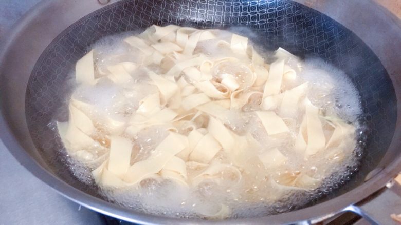 东北那疙瘩的美食★尖椒干豆腐,锅里下水，水开之后，把干豆腐放进去焯一下，并煮一会儿，大概煮2-3分钟就可以了。捞出来，备用。