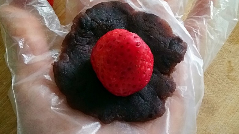 椰香草莓大福,将豆沙球压成薄饼状，放入一颗草莓。