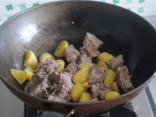 黑胡椒酱烧土豆,将排骨也倒入锅里，一起翻炒至排骨表面焦黄