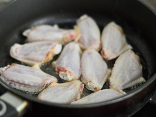 可乐鸡翅,锅里倒入少许油，烧热后将鸡翅皮朝下放入锅中，中火慢煎