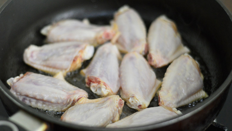 可乐鸡翅,锅里倒入少许油，烧热后将鸡翅皮朝下放入锅中，中火慢煎