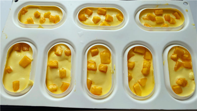 芒果淋面慕斯蛋糕,将剩余慕斯馅挤入模具，中间放上芒果丁。震几下放入冰箱冷冻12小时。