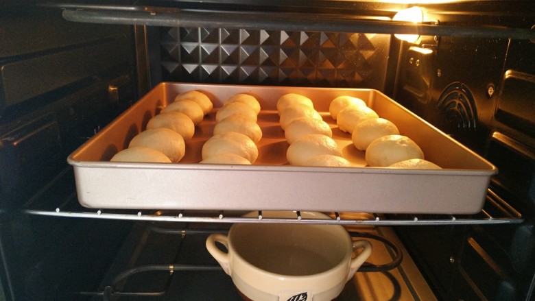 椰蓉牛奶小面包,将烤盘放入烤箱中，45°度二次发酵50分钟，记得在烤箱底部放一碗水，保持空气湿润