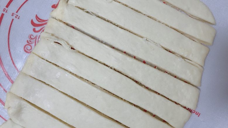 椰蓉奶棒面包,慢慢擀开，平铺成稍大些的长方形，用刀切成均匀的条状；