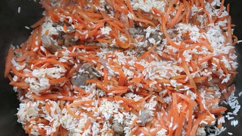 新疆特色羊肉抓饭,最后加入大米，搅拌均匀后，倒入开水，量不用太多，和平时焖米饭时的量差不多；