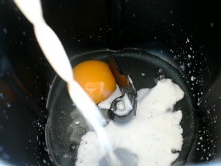 紫薯芋泥肉松包,将鸡蛋磕入面包机内，倒入牛奶