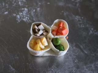 四喜蒸饺,将香菇、玉米、胡萝卜、豌豆粒分别填入孔中；