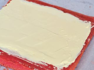 红丝绒蛋糕卷,蛋糕片切去一边，抹上淡奶油，卷起放冰箱冷藏半小时后再切。