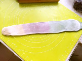 彩虹蛋黄酥,将松弛好的面团按照长条排列的方向，再次擀成长条，之后从浅色处开始卷起来