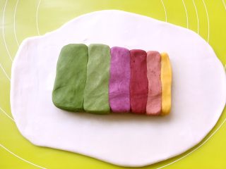 彩虹蛋黄酥,松弛好的水油皮面团擀成长方形，将6种颜色的油酥皮面团捏成同等长度，依次摆放在擀好的水油皮面团上