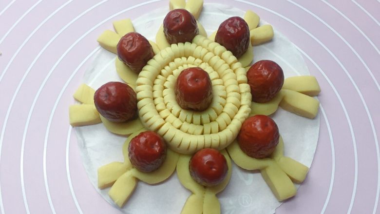 招财进宝枣花馍,把切好的长条卷起来，中间放一个红枣，然后放在枣花馍的中央位置，如上图。