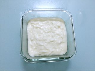 椰蓉奶冻,趁热把牛奶糊倒入保鲜盒中，抹平表面