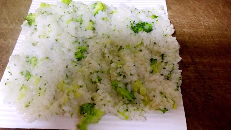 西兰花饭卷,抓匀的米饭和西兰花铺成薄薄一层，用手压匀