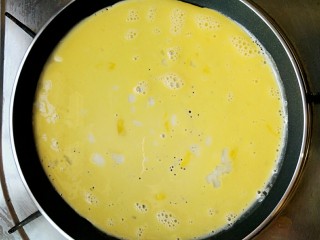 五彩素春饼,慢慢转动锅子，让蛋液均匀铺满整个锅子，煎个蛋皮。