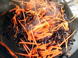五彩素春饼,锅中适量油，烧至7成热后，倒入胡萝卜丝和木耳丝，中火翻炒均匀。