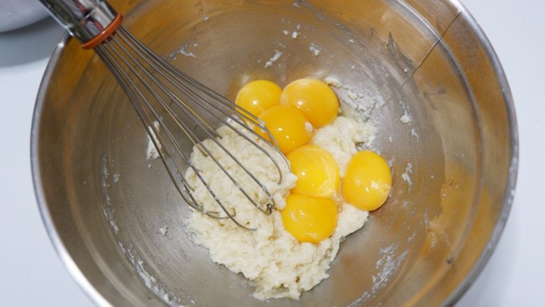 古早味蛋糕—烫面法,依次取出6个蛋黄一次性加入面糊中。