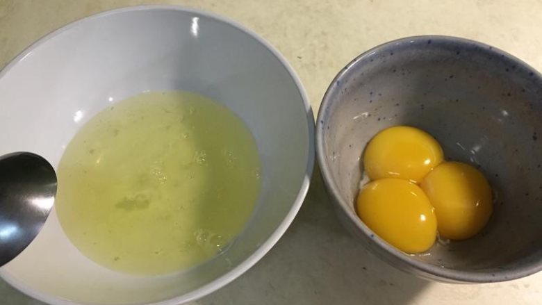 原味戚风蛋糕（6寸烫面法）,3個雞蛋將蛋黃和蛋白分開，蛋白可先加蓋放冰箱，等需要打發時再取出（冰的時候比較好打發）。（蛋白絕不能混入蛋黃，否則到時會無法打發，如果沒有把握，可以分三個碗弄出蛋黃，免得到時候有其中一個蛋黃破掉滴入蛋白中，使整碗都不能使用；蛋白也不能沾到水和油，否則一樣影響打發）