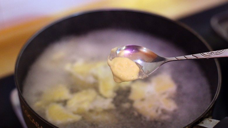 腊肠鲜虾盖浇面疙瘩,烧开一锅水，用勺子在热水中沾一下受热，沿碗边舀一小块面糊下入锅中。