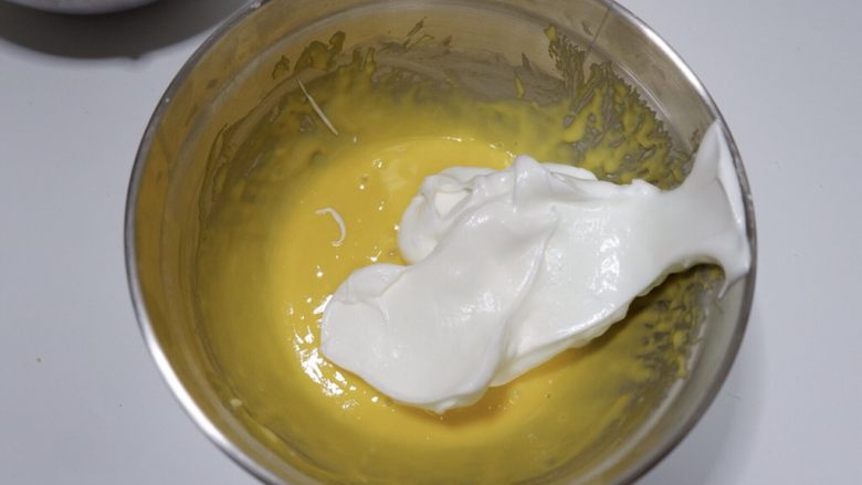 酸奶戚风蛋糕—烫面法,分三次将蛋白加入蛋糕糊中，先取1/3蛋白加入蛋糕糊中，搅拌至完全融合
