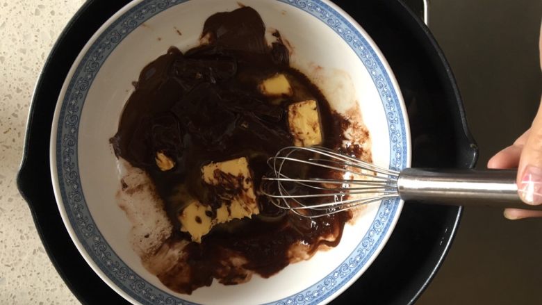 浓情布朗尼芝士蛋糕,现在制作布朗尼层：黑巧克力和黄油放入大碗内，坐一锅热水，水温不用太热，把巧克力和黄油隔水融化，用打蛋器搅拌